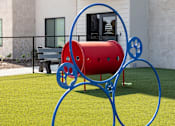 Thumbnail 8 of 17 - A red and blue sculpture resembling a dog is in the foreground of a grassy area.
