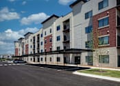 Thumbnail 15 of 17 - Apartment building with a parking lot in front.