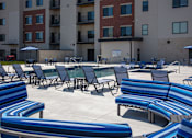 Thumbnail 7 of 17 - A sunny day at the outdoor seating area of a building with blue and white striped benches.