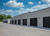 Thumbnail 3 of 17 - A long building with black garage doors.