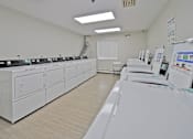 Thumbnail 11 of 29 - A clean, white-walled room with a series of white appliances on the left and a white washing machine on the right.