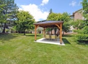 Thumbnail 29 of 35 - a patio with a table and chairs under a wooden pavilion