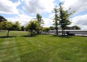 Thumbnail 34 of 35 - a grassy field with trees and a building in the background