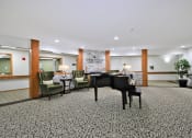 Thumbnail 26 of 35 - a large lobby with a piano and a table with chairs