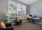 Thumbnail 15 of 21 - a living room with a desk and chairs and large windows