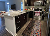 Thumbnail 2 of 21 - A kitchen with a white counter top and a rug on the floor.