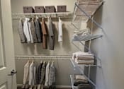 Thumbnail 7 of 21 - A hallway with a white door and a rack of ties and shirts.