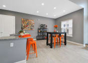 Thumbnail 12 of 21 - a dining room with a black table and orange stools