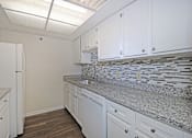 Thumbnail 15 of 41 - A kitchen with white cabinets and a granite countertop.