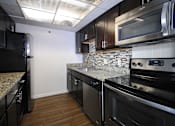 Thumbnail 18 of 41 - A kitchen with black cabinets and stainless steel appliances.