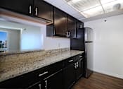 Thumbnail 19 of 41 - A kitchen with black cabinets and granite countertops.