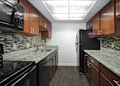 Thumbnail 16 of 41 - A kitchen with black appliances and wooden cabinets.