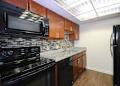 Thumbnail 17 of 41 - A kitchen with black appliances and wooden cabinets.