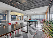 Thumbnail 28 of 41 - A pool table is in the middle of a room with a wooden table and red chairs.