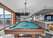 Thumbnail 29 of 41 - A pool table in a room with a high ceiling and a view of the outside.