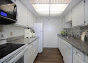 Thumbnail 20 of 44 - A kitchen with white cabinets and a black stove top oven.