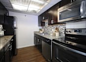 Thumbnail 18 of 44 - A kitchen with black cabinets and stainless steel appliances.