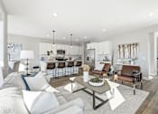 Thumbnail 8 of 44 - A modern living room with a white couch, a coffee table, and a kitchen area in the background.