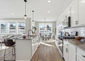 Thumbnail 1 of 44 - A modern kitchen with white cabinets and a wooden floor.