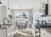 Thumbnail 5 of 44 - A modern kitchen with a large island and a view of the outdoors through the windows.