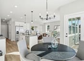Thumbnail 11 of 44 - A modern kitchen with a dining table and chairs.