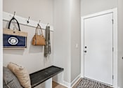 Thumbnail 40 of 44 - A hallway with a bench, coat rack, and a bag hanging on it.