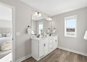 Thumbnail 32 of 44 - A bathroom with a vanity, mirror, and lighting fixtures.