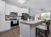 Thumbnail 1 of 26 - A kitchen with a granite countertop and a ceiling fan.