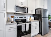 Thumbnail 2 of 26 - A modern kitchen with white cabinets and stainless steel appliances.