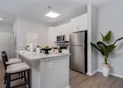 Thumbnail 4 of 26 - A kitchen with a stainless steel refrigerator, microwave, and wooden floors.