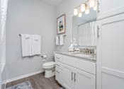 Thumbnail 8 of 26 - A white bathroom with a toilet, sink, and mirror.