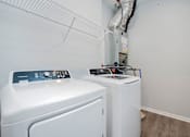 Thumbnail 17 of 26 - two washers and dryers in a laundry room with white walls and wood floors