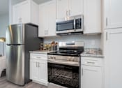 Thumbnail 9 of 26 - A modern kitchen with a stainless steel refrigerator, microwave, oven, and cabinets.