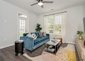 Thumbnail 12 of 26 - A living room with a blue couch and a ceiling fan.