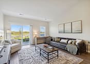 Thumbnail 6 of 18 - A modern living room with a large window and a view of a tree.