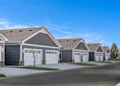 Thumbnail 2 of 18 - A row of houses with garages and driveways.