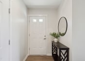 Thumbnail 8 of 28 - a hallway with a white door and a dresser with a vase on it