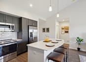 Thumbnail 4 of 18 - A modern kitchen with a white island and stainless steel appliances.