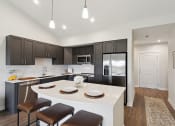 Thumbnail 1 of 28 - a kitchen with black cabinets and a white island with chairs