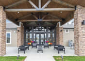 Thumbnail 22 of 28 - a covered patio with chairs and a large building