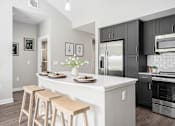 Thumbnail 4 of 42 - A kitchen with a white island and black cabinets.