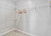 Thumbnail 14 of 42 - A white closet with a hanging dress and a carpet on the floor.