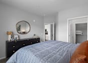 Thumbnail 8 of 53 - A bedroom with a blue bedspread and a brown leather couch.