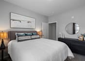 Thumbnail 9 of 53 - A bedroom with a large bed, a painting on the wall, and a round mirror above a dresser.