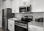 Thumbnail 3 of 53 - A black refrigerator and oven in a kitchen with white cabinets.