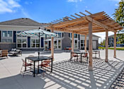 Thumbnail 25 of 53 - A patio with a table and chairs under a wooden pergola.