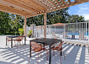 Thumbnail 26 of 53 - A patio with a table and chairs under a wooden pergola.