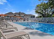 Thumbnail 22 of 53 - A pool with sun loungers and a building in the background.