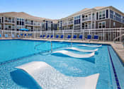 Thumbnail 51 of 53 - A large swimming pool with a white diving board in front of a building.