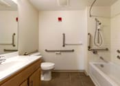 Thumbnail 10 of 16 - A white bathroom with a toilet, sink, and bathtub.
